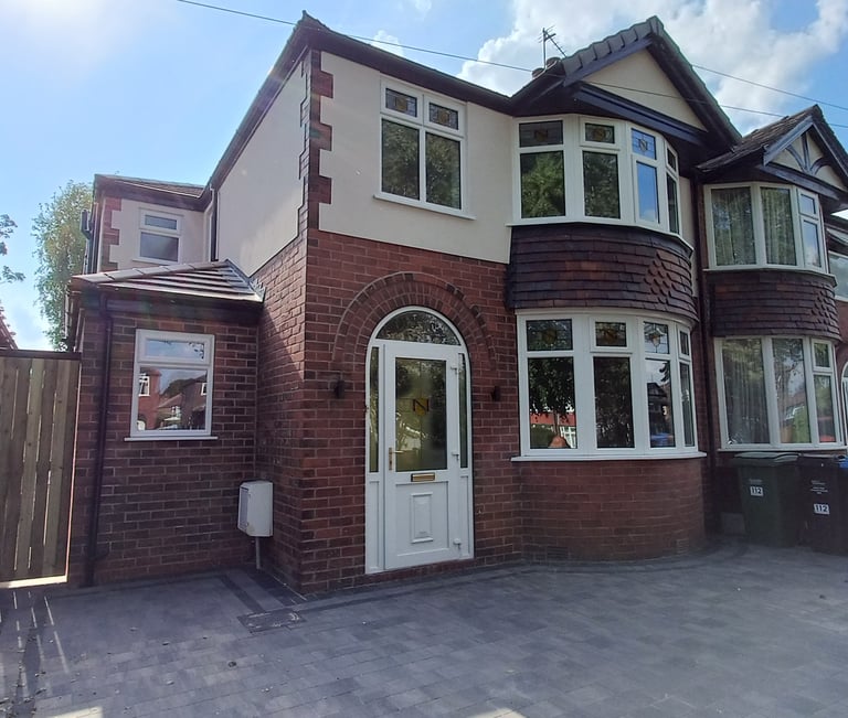 A renovated semi-detached red brick house featuring a modern paved driveway and white uPVC bay windows.