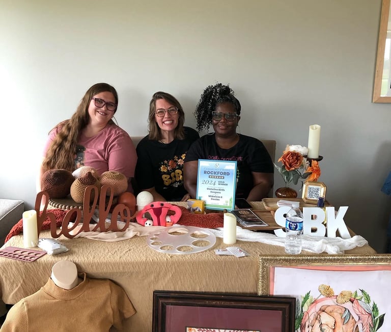 a group of women sitting at a table with doula items around them