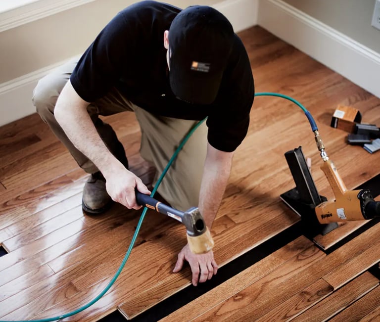Hardwood floors installer installing prefinished hardwood using air nailer.