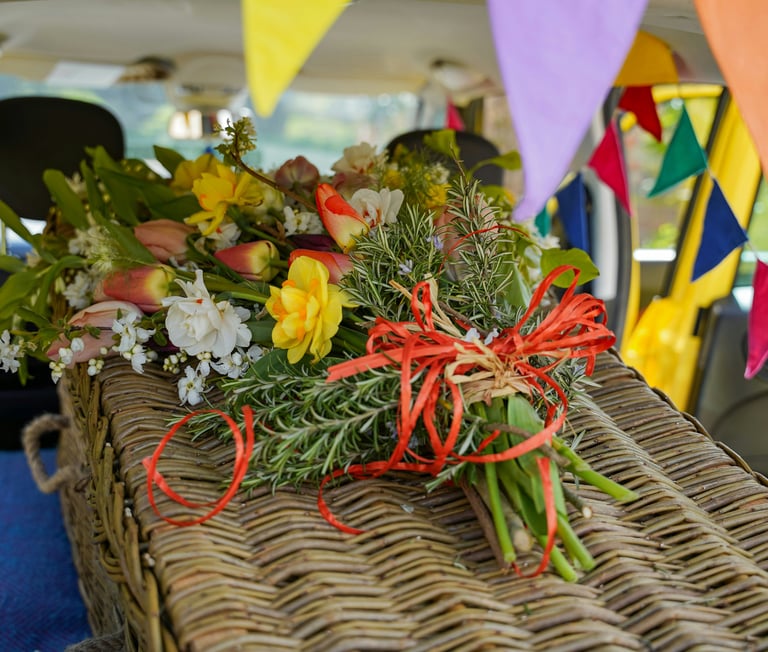 Wicker casket decorated with brightly colour flowers and bunting
