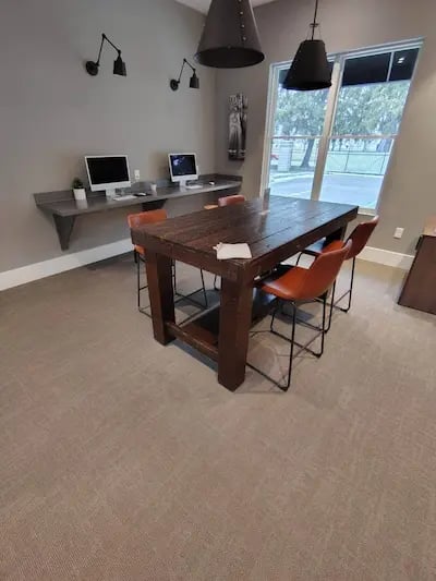 Picture of an office with two computer monitor and a table with four red chairs