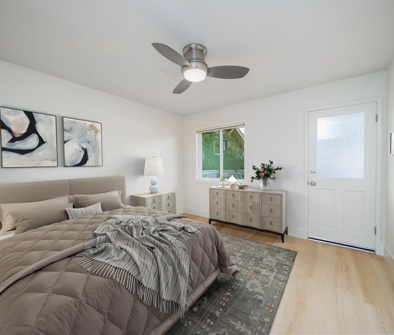 Bright modern bedroom with upholstered bed, contemporary artwork, wood flooring, and stylish neutral furnishings.