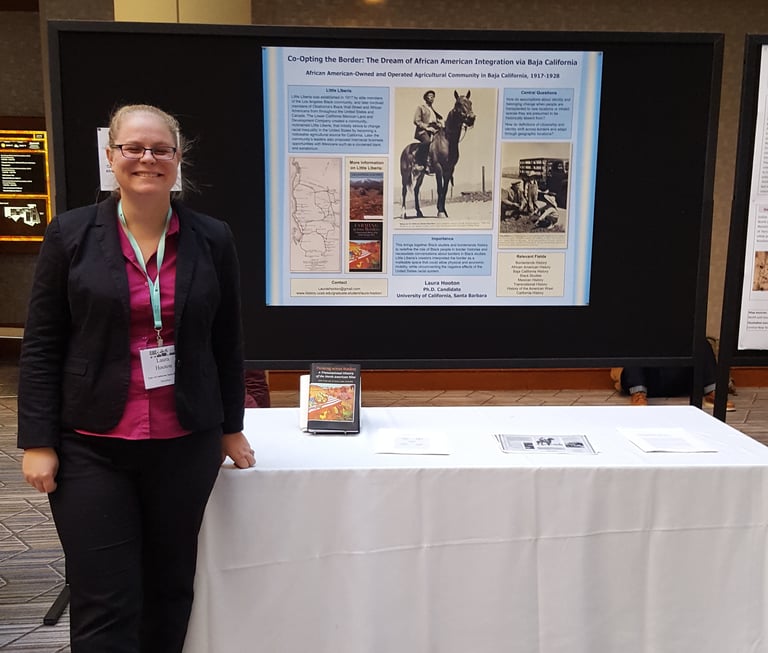 Laura Hooton, left, standing with Little Liberia poster, AHA 2017