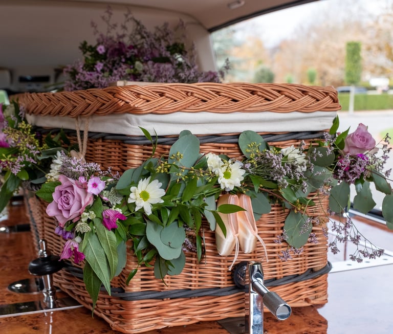 Wicker funeral casket decorated with fresh flowers