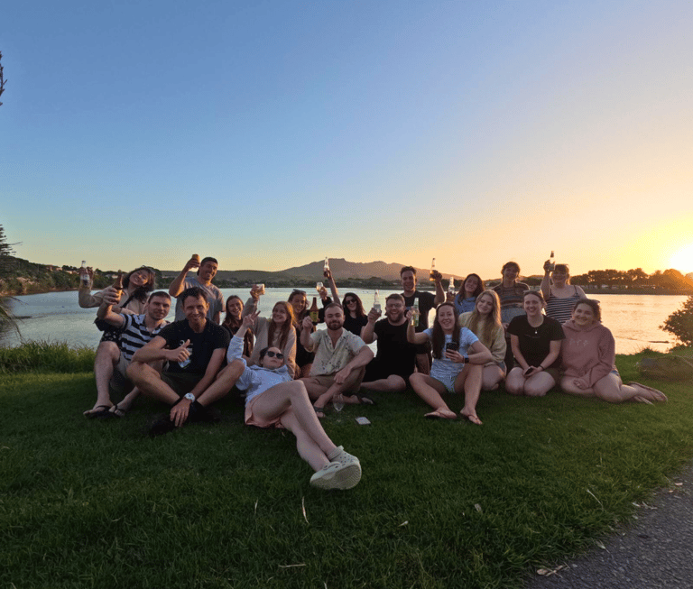 a lovely chilli tours group enjoying a drink at sunset in new zealand