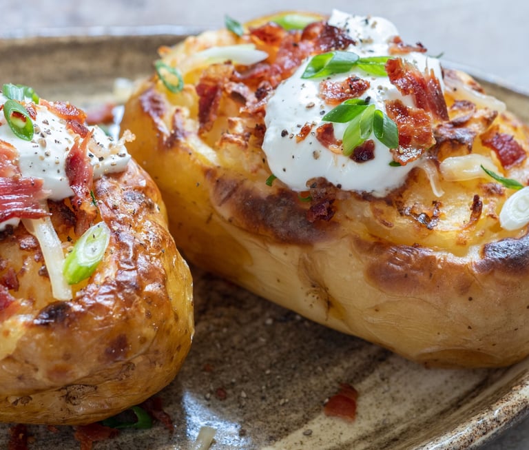 Golden-brown potato skins filled with creamy whipped potatoes, topped with melted cheese and crispy 