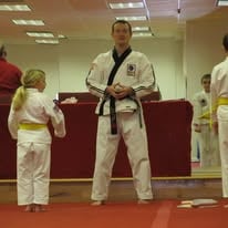Martial arts instructor in a black belt dobok leading a Tang Soo Do class with young students.