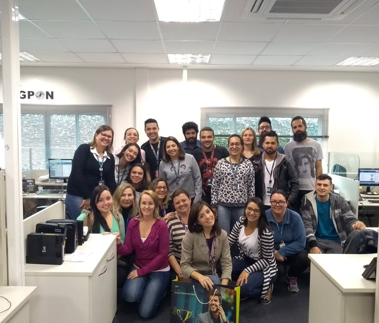 uma equipe de trabalho, um grupo de pessoas em pé ao redor de uma mesa posando para uma foto