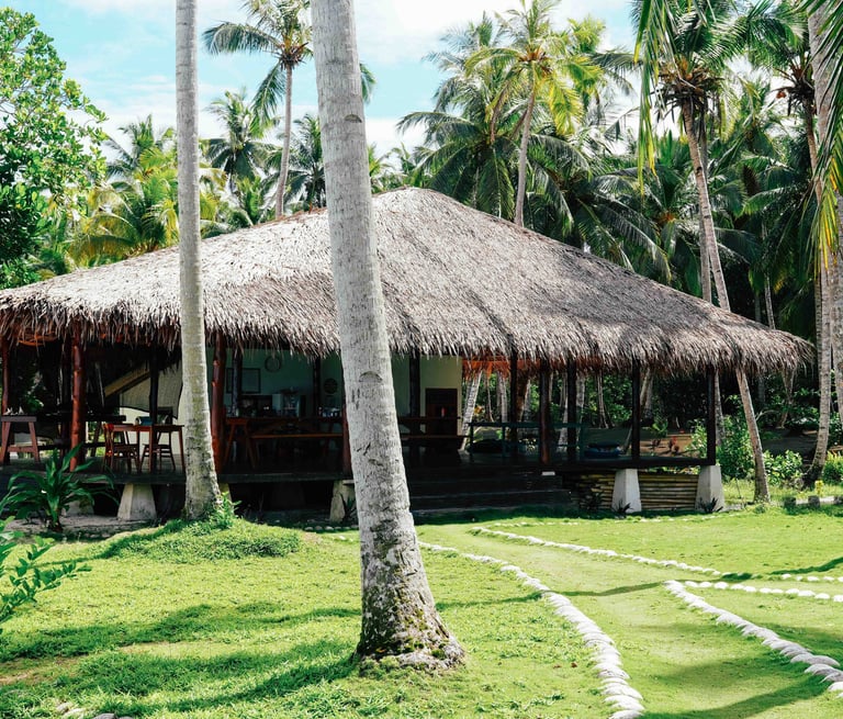 Open-air dining pavilion at Toska eco-resort surrounded by tropical palm trees