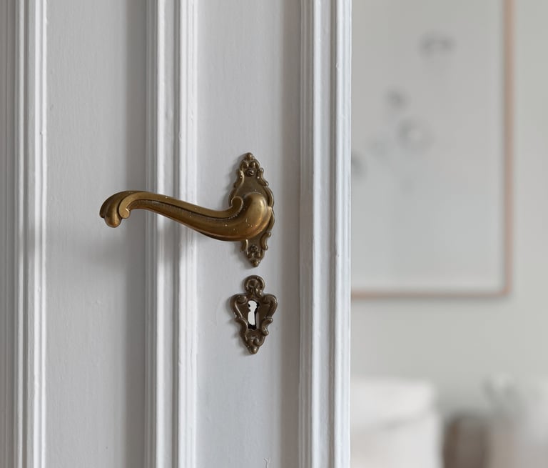 White door with ornate brass door handle and keyhole