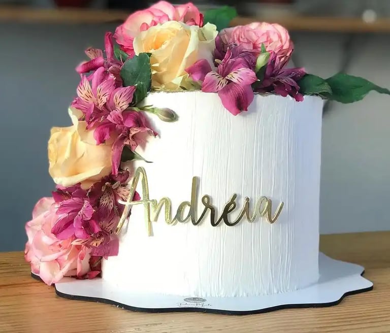 Bolo decorado com flores coloridas e nome "Andreia" em destaque. Ideal para festas e celebrações.