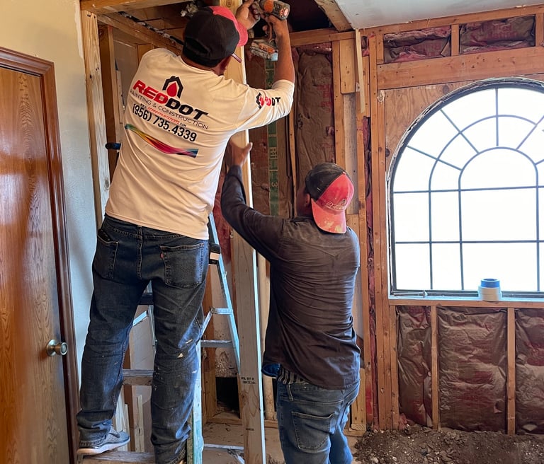 Professional contractors installing wood wall framing during a home interior renovation project.