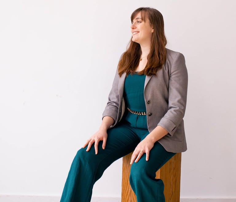 Rachel Krayenhoff in a teal jumpsuit and grey blazer posing for a business headshot.