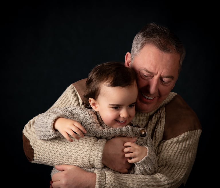 A smiling father hugs his happy young daughter in a heartwarming family portrait.
