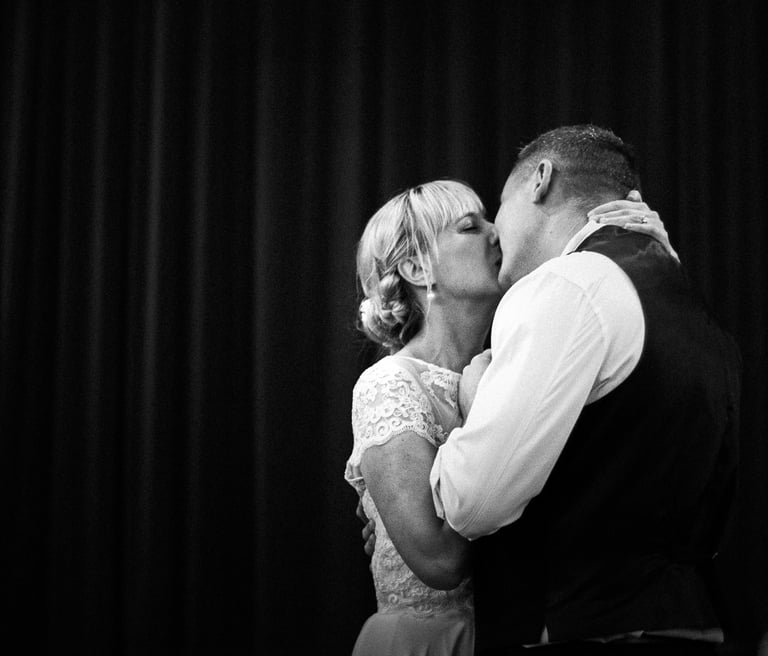 a bride and groom kissing in a black and white photo