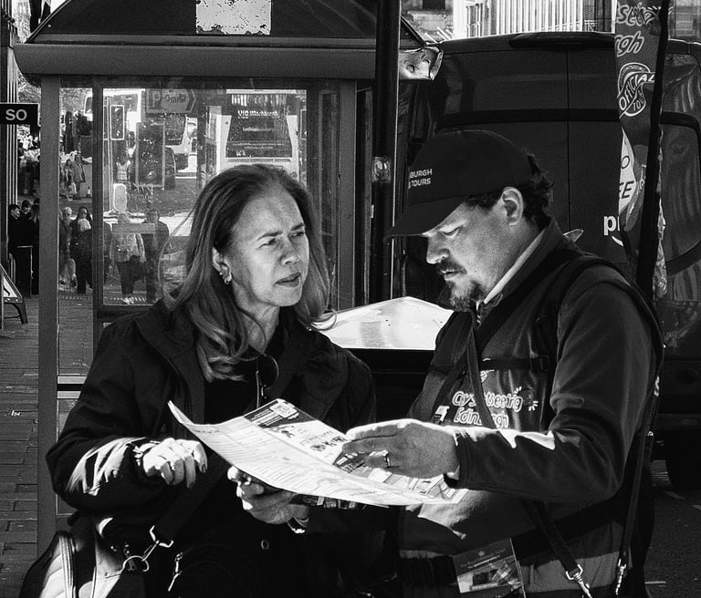 A woman tourist chats with a tour guide, who is holding a map, looking for directions. Waterloo Place, Edinburgh