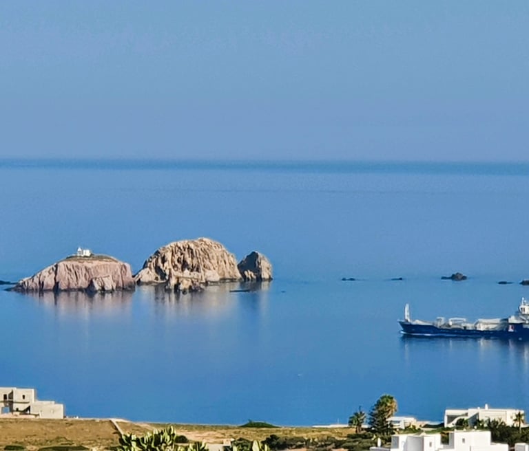 Sea scape of Paros looking to the sea, small rocky islands and a comertial vesel