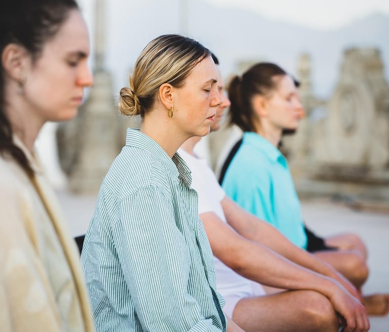 Group of four women meditating in cross-legged position, with their eyes closed