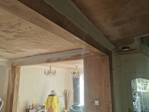 Freshly plastered ceiling and walls in a home renovation project featuring a structural steel beam.