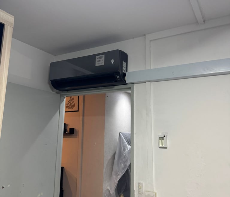 Modern black wall-mounted split air conditioner installed above an interior doorway for efficient home cooling.