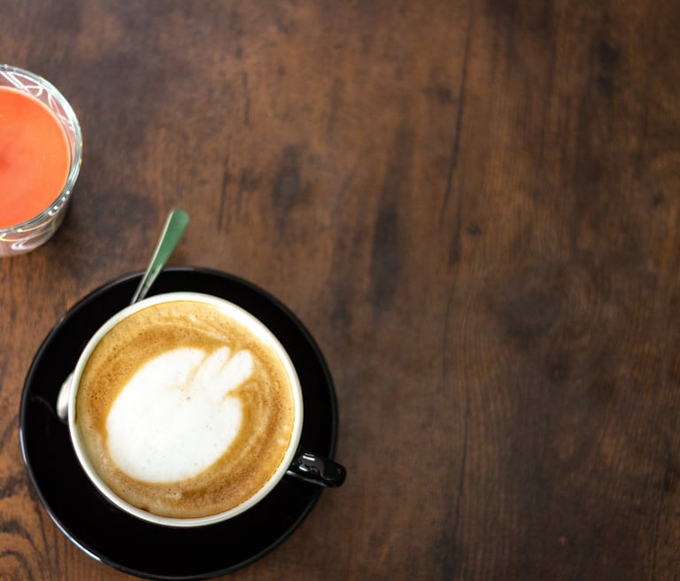 Hot cappuccino with latte art and a lit candle on a rustic wooden table.