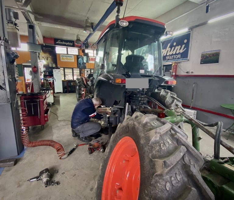 ένας μηχανικός τρακτέρ επισκευάζει ένα τρακτέρ με κουβούκλιο μέσα στο συνεργείο - kotsou tractors