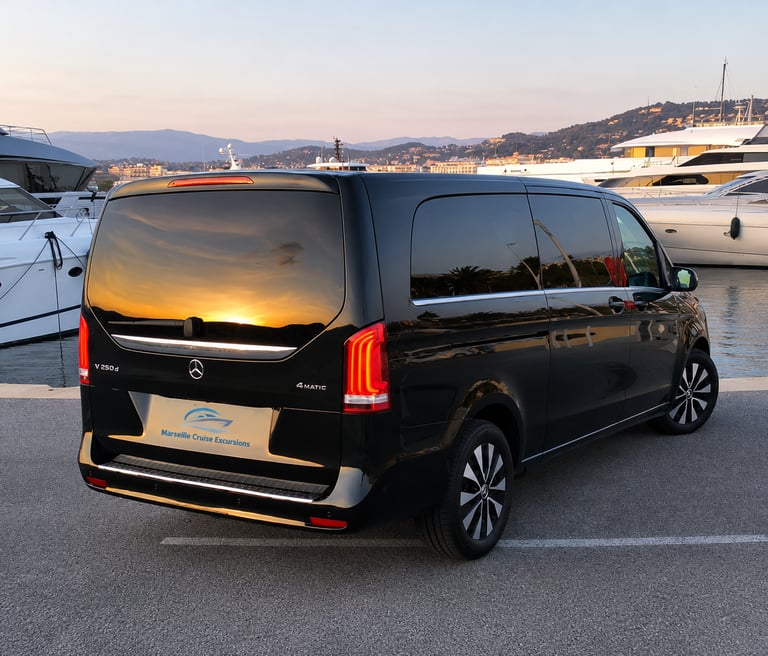 Black Mercedes V-Class luxury van parked at a harbor with yachts during sunset.
