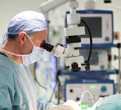 Figura de médico olhando no microscópio para neurocirurugia minimamente invasiva