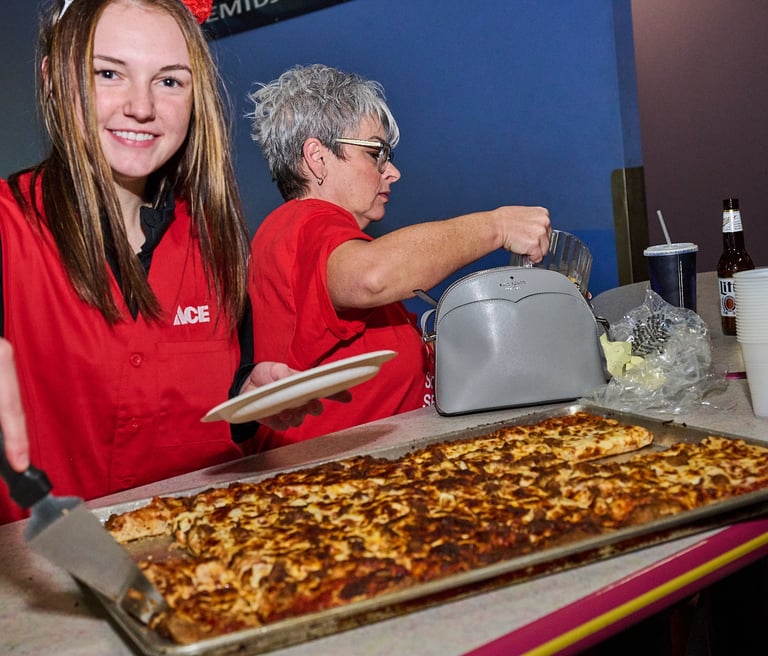 a girl in a red vest is cutting a pizza