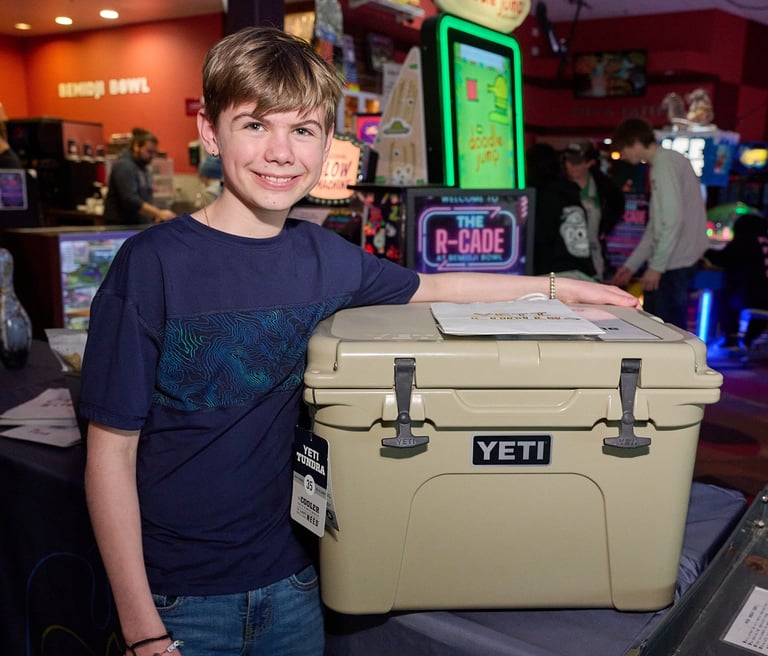 a boy standing next to a prize which is a cooler