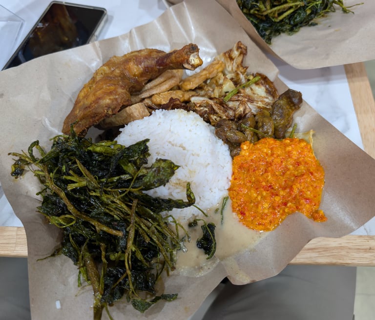 Ma Nasi Ayam Goreng with fried chicken, white rice, spicy sambal, and sautéed greens on brown paper.