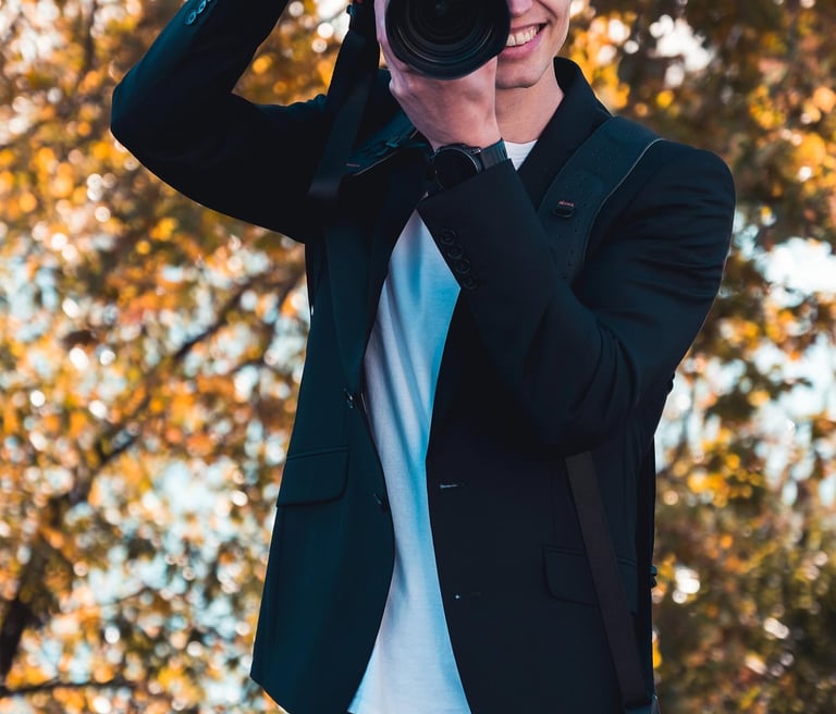 Fotograf Joel Pingel fotografiert lächelnd in herbstlicher Umgebung. Action-Portrait von Just Perspectives.