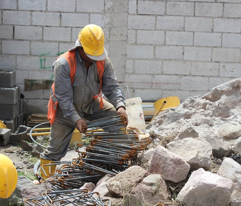 a man in a yellow helmet working with construction materials