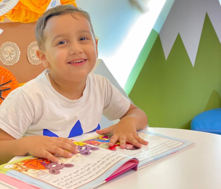 Smiling boy reading a colorful storybook at a kids' learning center