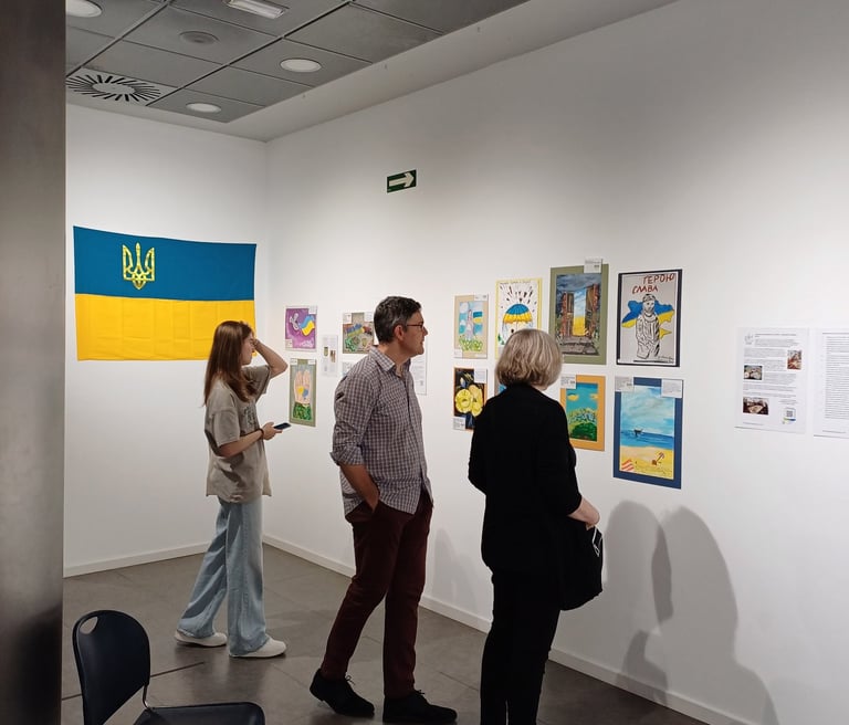 Visitors at the Spanish art gallery with paintings made by kids affected by the war in Ukraine