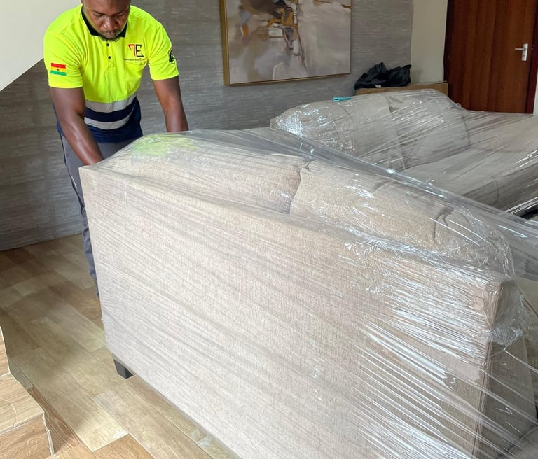 A professional mover wearing a bright yellow high-visibility vest with "TE Transporter Express" logo