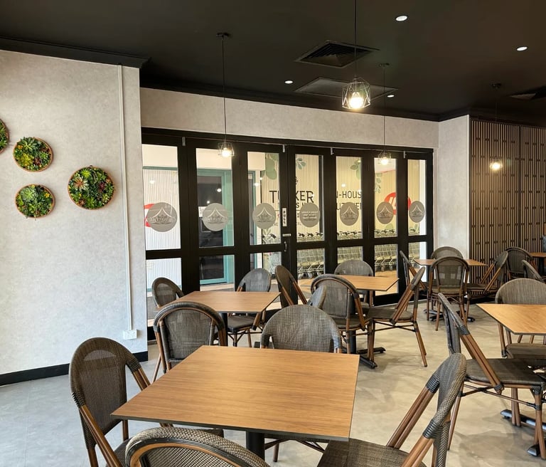 Modern cafe interior with wooden tables, woven chairs, and decorative wall succulents.