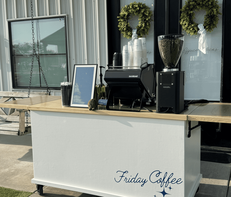 Mobile espresso bar setup with an espresso machine and coffee bean grinder on a white cart.