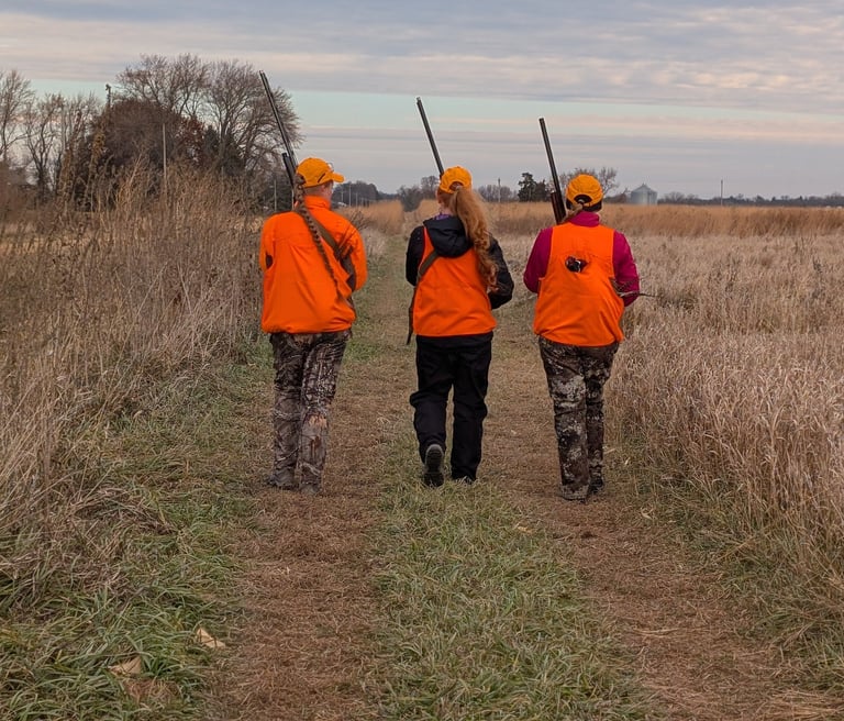 Three women hunters walking in a field.