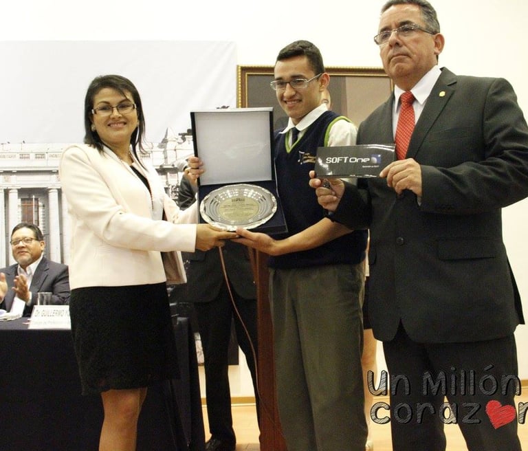 A smiling student receives an academic award and a SoftOne gift from officials at a formal ceremony.