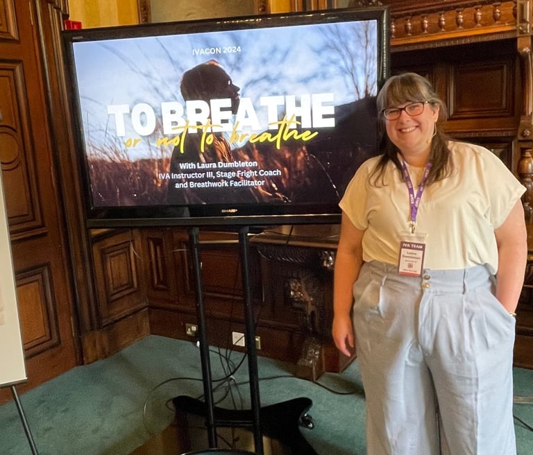 Laura is smiling towards the camera standing in front of her presentation on breathwork