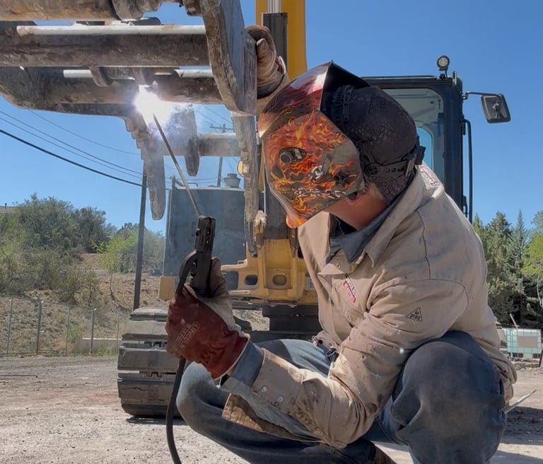 a man in a welding helmet welding a piece of equipment