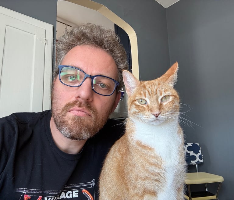 Photo of Hank with his ginger cat Pippin. They both have the same facial expression.