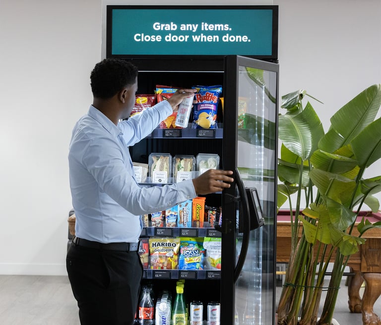 man opening AI smart vending machine door to grab a snack
