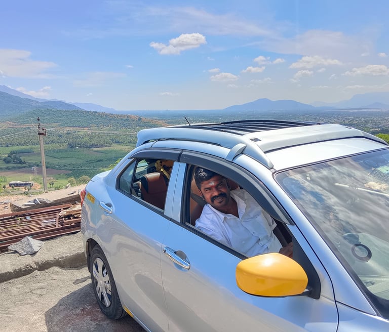 South India Drop Taxi service car traveling through a scenic mountain route"