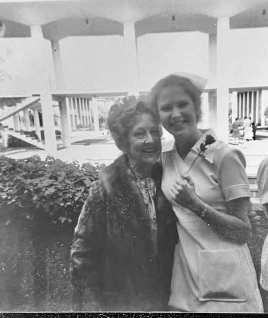 Vintage black and white photo of a smiling young nurse in uniform posing with an older woman.