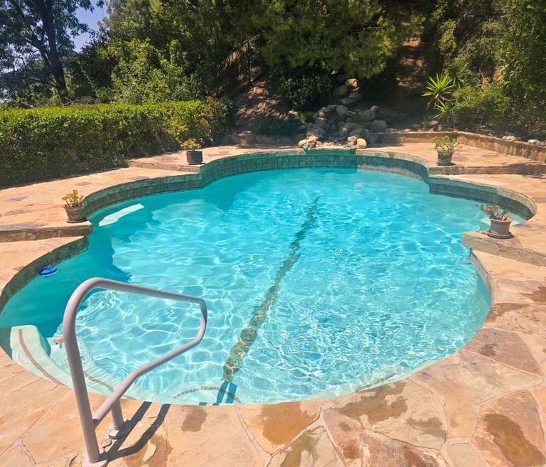 Natural stone pool with custom patio, cleaned and maintained by Piscus Pools – ideal for homeowners seeking nature-inspired 