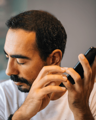 Man with refractive error using adaptive technology screen reading software on cell phone accessible