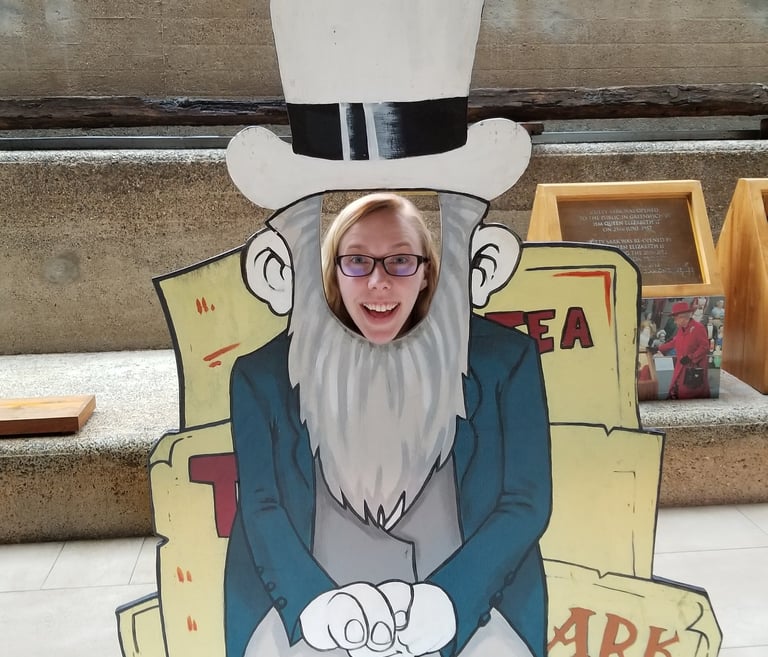 Sarah Schedler, book editor, poses smiling with her face poking through a wooden cut-out.