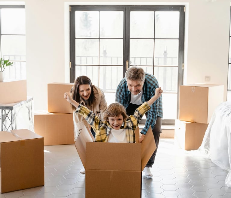 a family moving into a new house, boxes with a child in a cardboard box